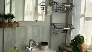 A bathroom with a white sink, mirror, and two black wire baskets on the wall.