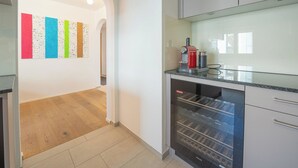 Una cocina moderna con horno empotrado, cafetera y vistas a un pasillo con obras de arte coloridas a través de un arco.