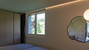 Une chambre à coucher avec un lit, une fenêtre donnant sur un beau paysage, une horloge murale et un petit haut-parleur.