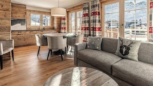 Een gezellige woonkamer met een bank, een rond bijzettafeltje en een eethoek met stoelen en een tafel.