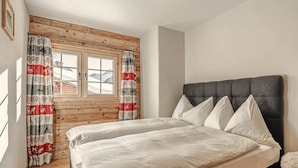 Een slaapkamer met een bed, een raam met gordijnen en een houten wand.