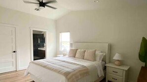 A bedroom with a bed, bedside table, lamp, ceiling fan, and a door. - Modern South ATX - 3BR - Fast WiFi - Free Parking (Austin)