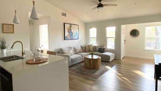 A spacious living room with a large sofa, a coffee table, pendant lights, and a ceiling fan. - Modern South ATX - 3BR - Fast WiFi - Free Parking (Austin)