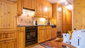 A kitchen with wooden cabinets, a stove, and a coffee maker. - Rothornblick 19 Appartement/Fewo, Bad, WC, 3-Bettwohnung Rothornblick 19 by Interhome (Arosa)
