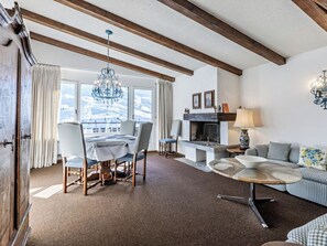 A room with a dining table, chairs, a sofa, a fireplace, and a chandelier. - Haus Duranna 7 Appartement/Fewo, Bad, WC, 4-Bettwohnung by Interhome (Arosa)