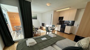Een hotelkamer met een bed, een bureau, een stoel, een kitchenette en uitzicht.