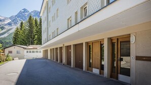 Een hotel met een rij kamers, een overdekte gangpad en een berg op de achtergrond.