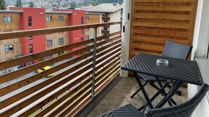 Een balkon met uitzicht op een stad, houten leuningen en een tafel met stoelen.