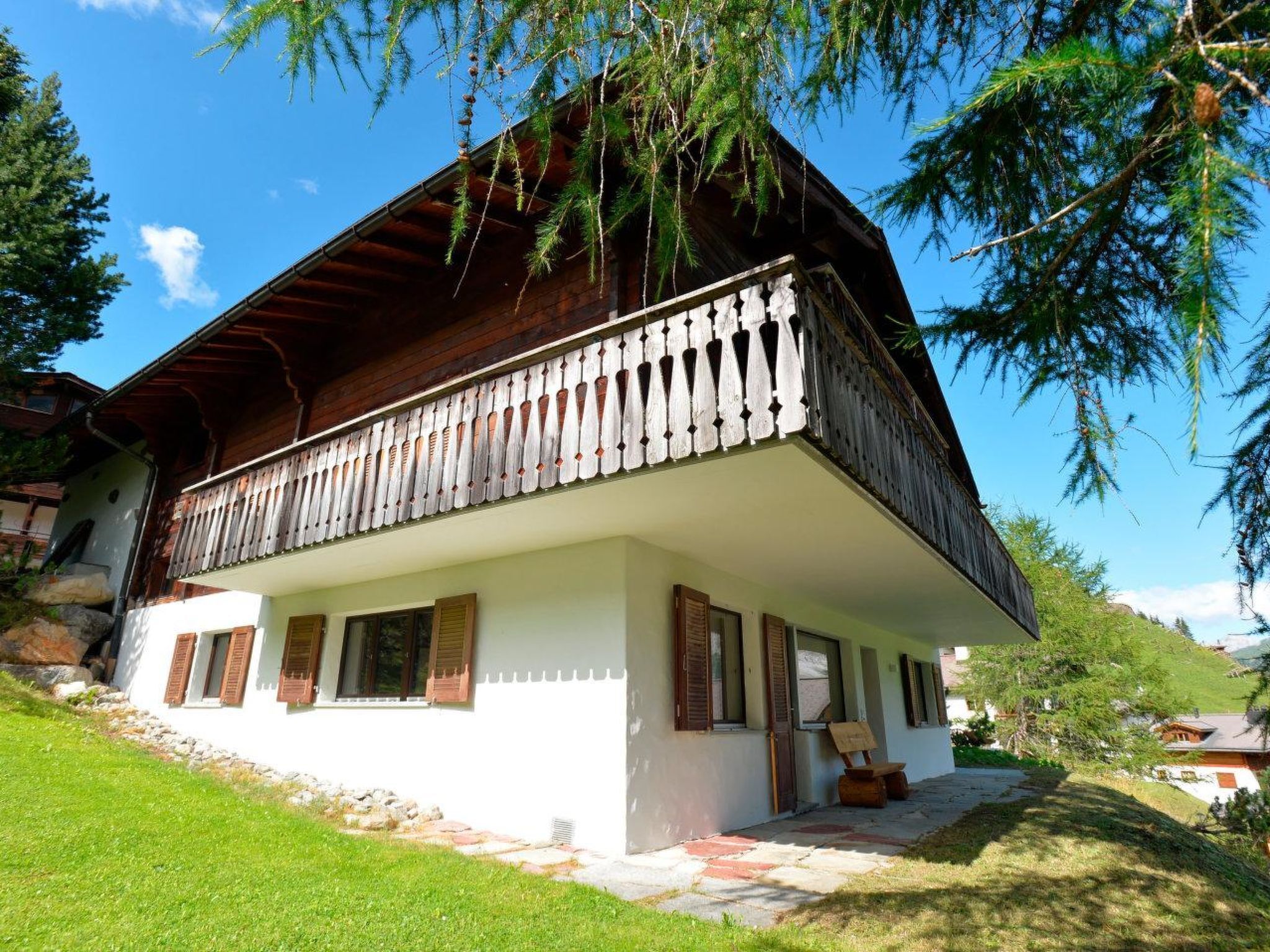Ein Chalet mit Balkon, Steinunterbau und Holzhörner.