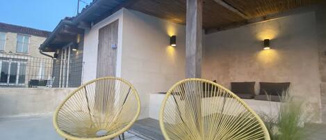 Two wicker chairs outside a building with a concrete floor and a metal roof.