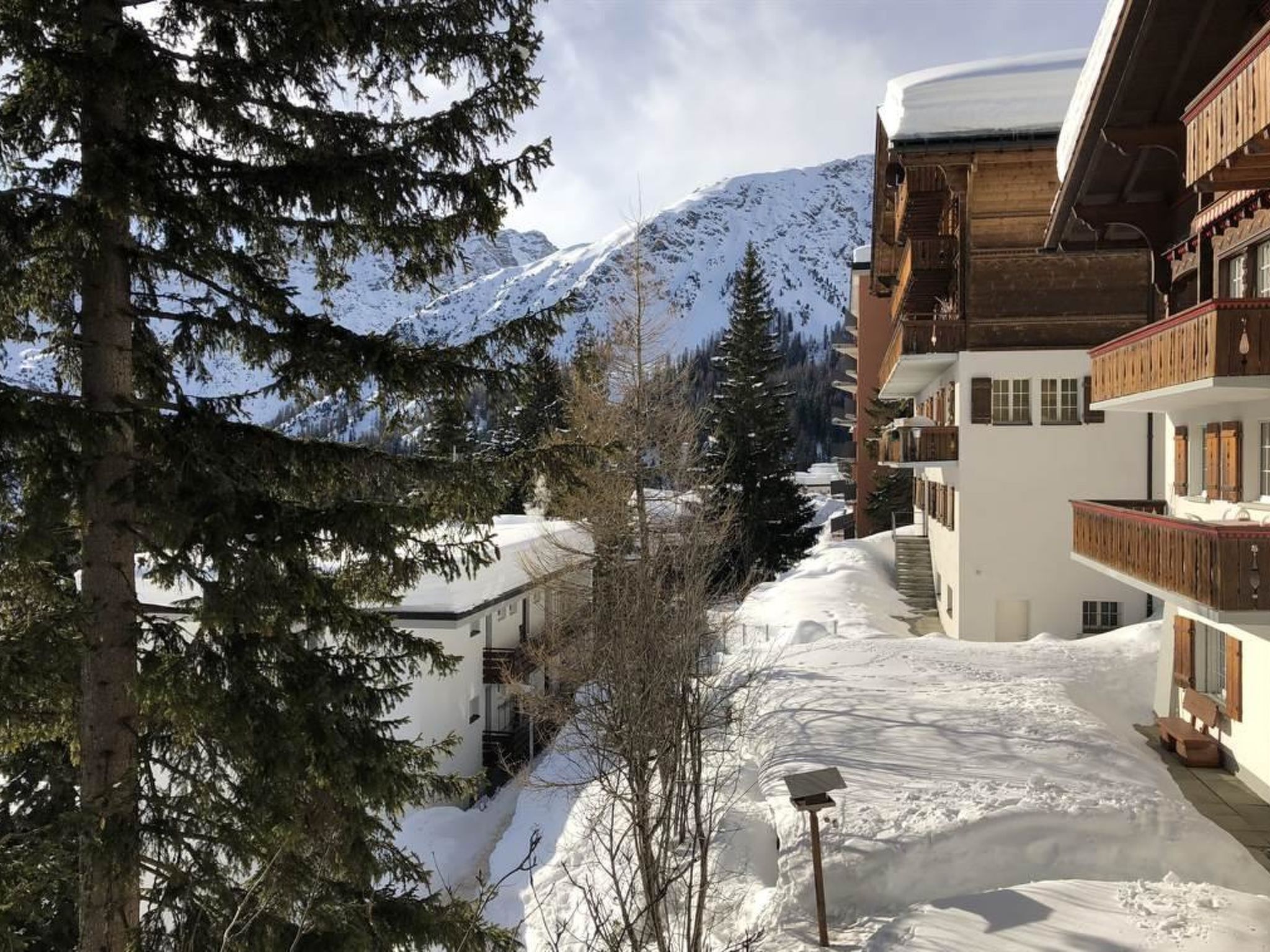 A snow-covered mountain landscape with a building featuring balconies and a snow-covered roof.