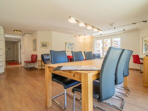 A modern dining area with a wooden table and blue chairs, a wooden floor, and artwork on the walls. - Camana Wohnung EG Appartement/Fewo, Dusche oder Bad, WC, 6-Bettwohnung Camana EG by Interhome (Arosa)