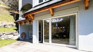 Ein modernes Gebäude mit einer Steinschrankwand, einer Holzpergola und einer großen Schiebeglastür.