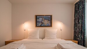 Ein Hotelzimmer mit einem Bett, zwei Nachttischlampen, einem Bild an der Wand und einem Vorhang.