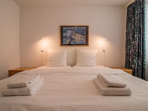 A hotel room with a bed, two bedside lamps, a painting on the wall, and a curtain. - Camana Wohnung EG Appartement/Fewo, Dusche oder Bad, WC, 6-Bettwohnung Camana EG by Interhome (Arosa)