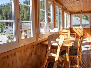 Un interior de madera con ventanas amplias, una mesa y sillas.
