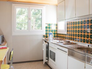 Eine kleine Küche mit Fenster, einem Herd und einer Mikrowelle.