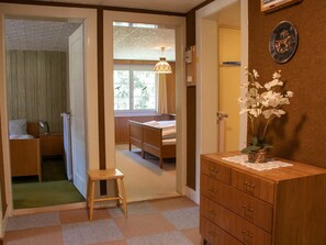 A room with a bed, a nightstand, a dresser, a small stool, and a window with a view of trees. - Chalet Methfessel 2 by Arosa Holiday Appartement/Fewo, Dusche oder Bad, WC, 3 Sc by Interhome (Arosa)