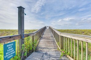 A wooden boardwalk leading to a pool with a sign instructing to rinse off sand before entering. - 🏖️ Emerald Surf 204 | Beachfront Navarre Beach | Free Beach Service + Gear (Navarre Beach)