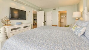 Un dormitorio con cama, televisor, cómoda y ventilador de techo.