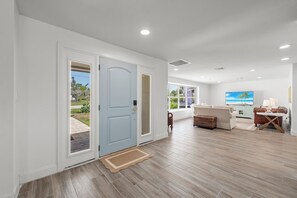 Ein modernes Interieur mit einer hellblauen Tür, einer Sitzecke mit Fernseher und Blick ins Freie.