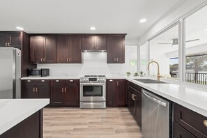 Una cocina moderna con armarios de madera oscura, electrodomésticos de acero inoxidable y un ventanal con vistas al exterior.