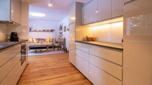 Eine moderne Küche mit weißen Schränken, Holzboden und einem Essbereich mit Sofa und Tisch.