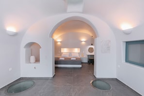 A modern bedroom with a bed, bedside tables, and a window. - Agave Cave Studios (Santorini)