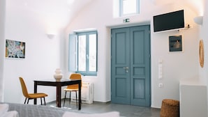 Een kamer met een bed, een tafel met stoelen, een raam, een deur en een tv aan de muur.