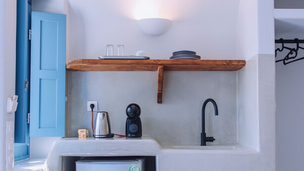 Een compacte kitchenette met een geïntegreerde koelkast, koffiezetapparaat en een gootsteen.