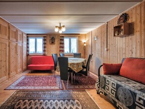 A cozy room with a red sofa, a dining table with chairs, and a patterned rug. - Nühus 1. OG Appartement/Fewo, Bad, WC, 6-Bettwohnung by Interhome (Arosa)