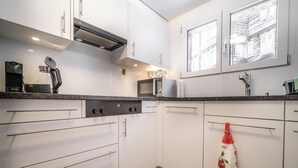 Eine moderne Küche mit weißen Schränken, einer eingebauten Mikrowelle und einer Kaffeemaschine.