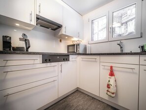 A modern kitchen with white cabinets, a built-in microwave, and a coffee maker. - Nühus 1. OG Appartement/Fewo, Bad, WC, 6-Bettwohnung by Interhome (Arosa)