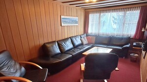 A cozy living room with a black leather sofa, a wooden coffee table, and a rocking chair. - Chalet Suveran 1 Appartement/Fewo, Bad, WC, 6-Bettwohnung Suveran 1 by Interhome (Arosa)