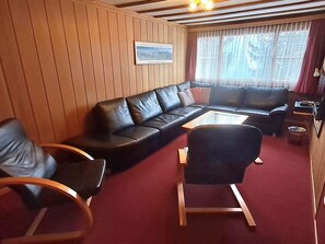Ein gemütliches Wohnzimmer mit einem schwarzen Ledersofa, einem Holztisch und einem Schaukelstuhl.