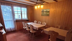 A dining area with a wooden table and chairs, a window with curtains, and a painting on the wall. - Chalet Suveran 1 Appartement/Fewo, Bad, WC, 6-Bettwohnung Suveran 1 by Interhome (Arosa)