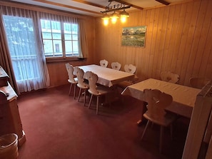 Ein Essbereich mit Holztisch und Stühlen, einem Fenster mit Vorhängen und einem Bild an der Wand.