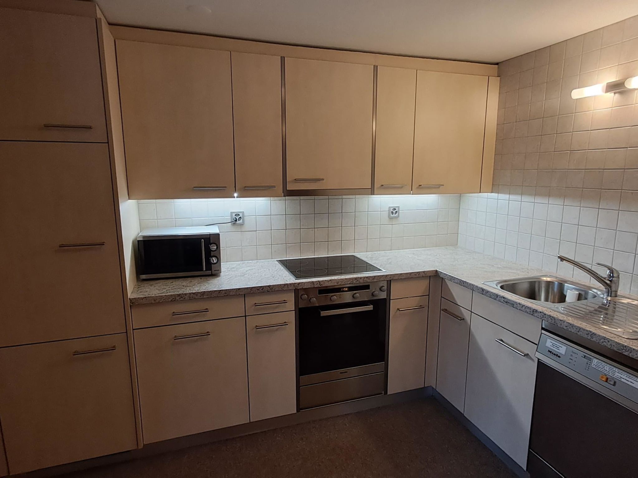 A kitchen with beige cabinets, a microwave, a dishwasher, and a sink.