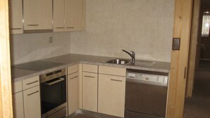A compact kitchen with a dishwasher, oven, and a sink. - Chalet Suveran 1 Appartement/Fewo, Bad, WC, 6-Bettwohnung Suveran 1 by Interhome (Arosa)