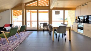 A spacious living area with a dining table, chairs, a sofa, and a kitchen area. - Erzhornblick Appartement/Fewo, Dusche und Bad, WC, 3 Schlafräume by Interhome (Arosa)