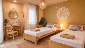 Ein Schlafzimmer mit zwei Betten, einem Schreibtisch, einem Stuhl, einem Spiegel, einer Wanddekoration und einer Pendelleuchte.