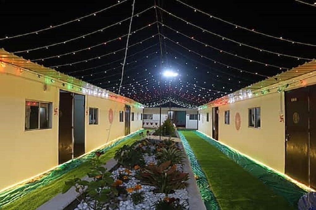 A corridor with string lights, a central pathway, and a small garden area.