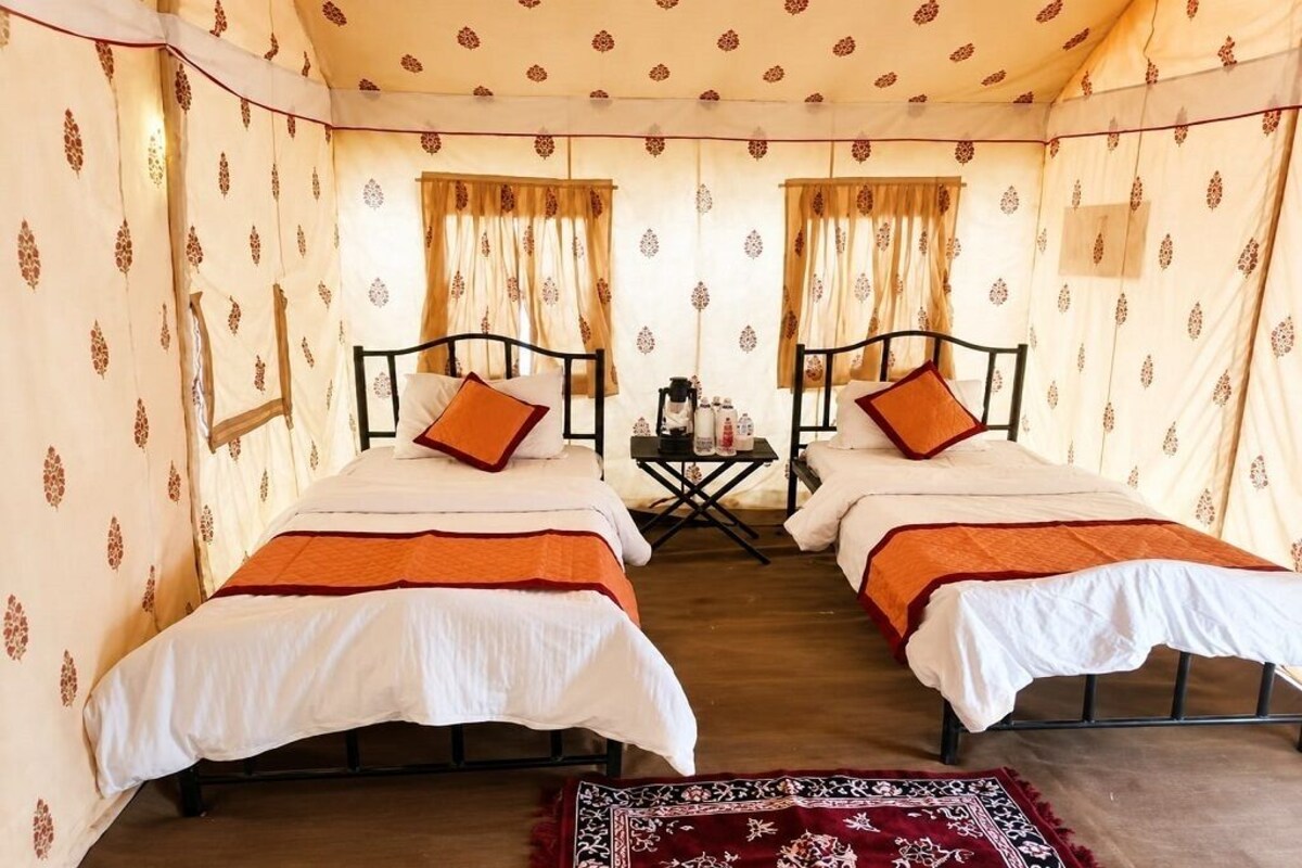 Une chambre avec deux lits, une petite table et des rideaux.
