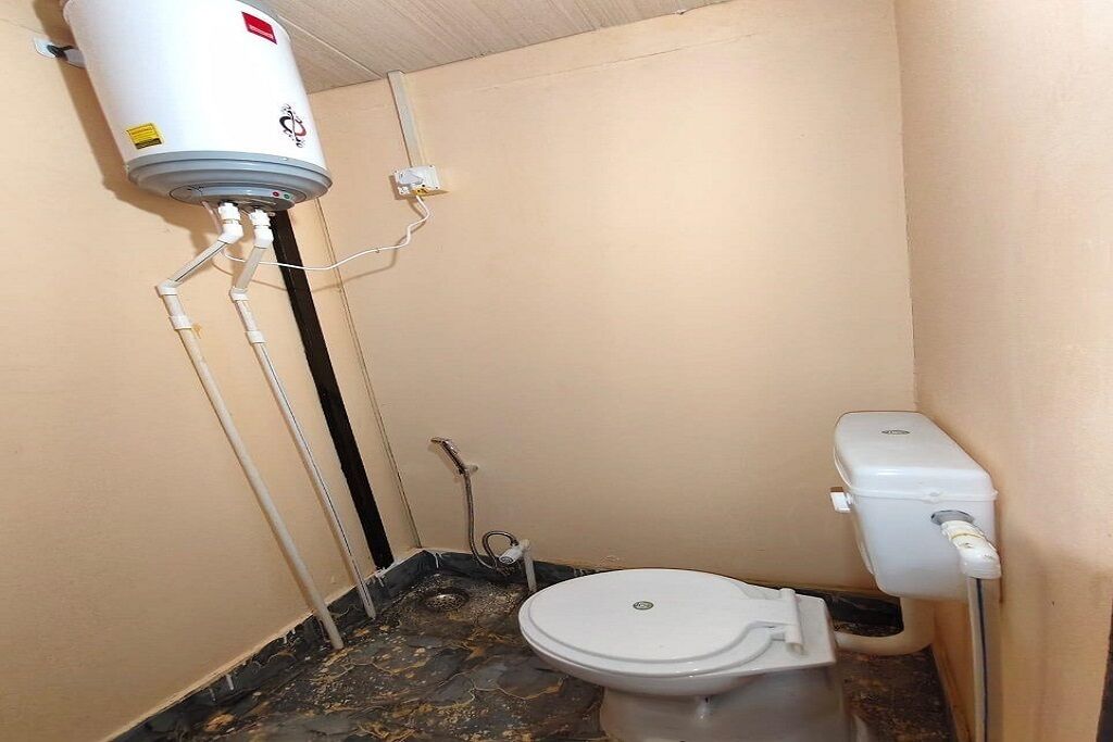 Ein kleines Badezimmer mit Toilette, Warmwasserbereiter und Dusche.