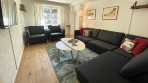 A living room with a sofa set, a coffee table, and a window with curtains. - Pradella Garten by Arosa Holiday Appartement/Fewo, Dusche oder Bad, WC, 7-Bettwo by Interhome (Arosa)