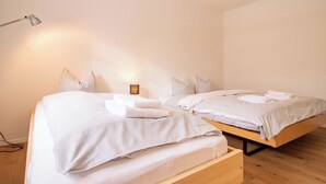 A bedroom with two beds, a bedside lamp, and a hanging light fixture. - Pradella Garten by Arosa Holiday Appartement/Fewo, Dusche oder Bad, WC, 7-Bettwo by Interhome (Arosa)