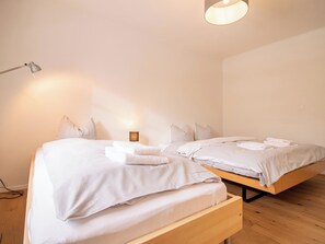 A bedroom with two beds, a bedside lamp, and a hanging light fixture. - Pradella Garten by Arosa Holiday Appartement/Fewo, Dusche oder Bad, WC, 7-Bettwo by Interhome (Arosa)