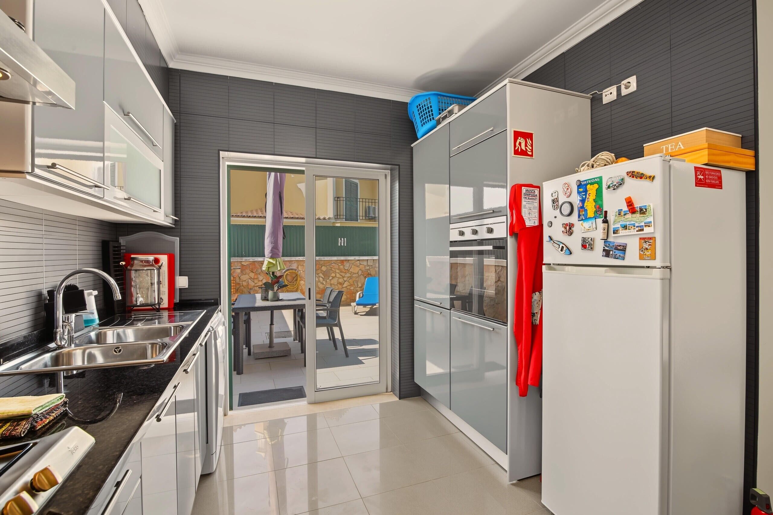 A modern kitchen with a built-in oven, a refrigerator, and a dining area with a table and chairs.