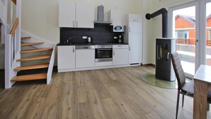 Una cucina moderna con mobili bianchi, forno integrato, microonde e stufa a legna.