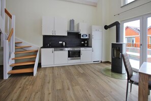 A modern kitchen with white cabinets, a built-in oven, and a wood-burning stove. - Appartement Hafenflair am Plauer See (Plau am See)
